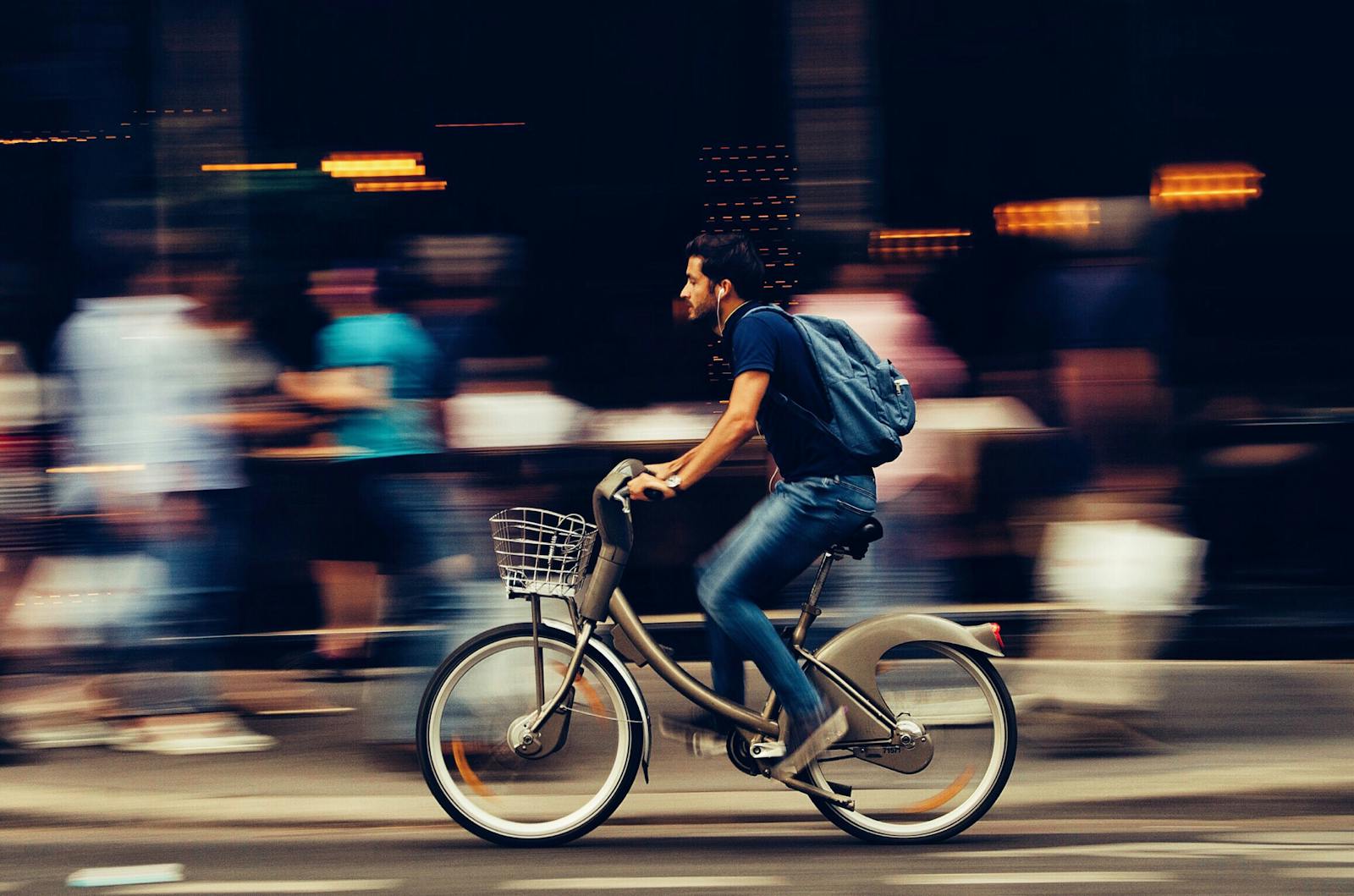 A cyclist swiftly rides through an urban street, capturing the essence of city life and motion.