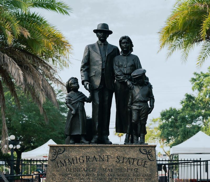 A monument honoring immigrants in Ybor City, Tampa, Florida under palm trees.