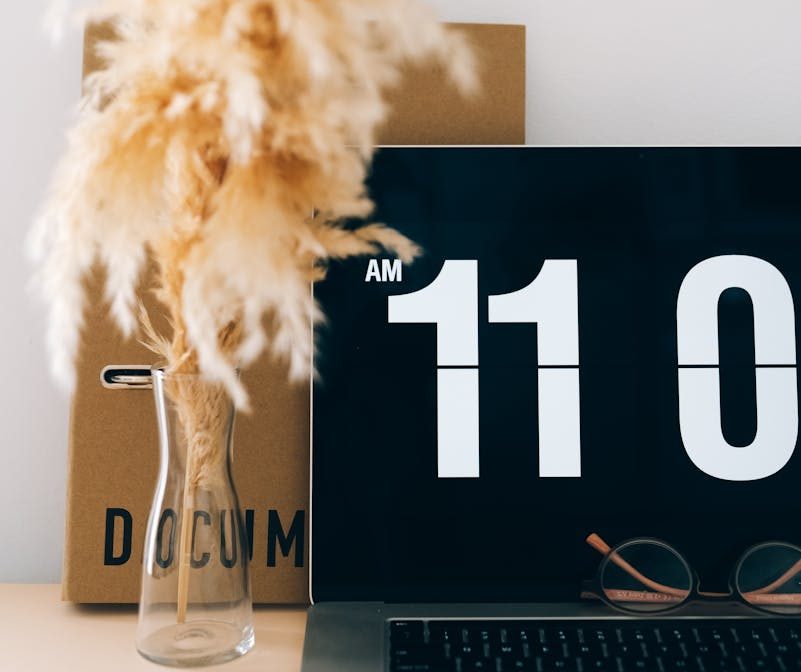 Contemporary office with digital clock screensaver and decorative pampas grass.